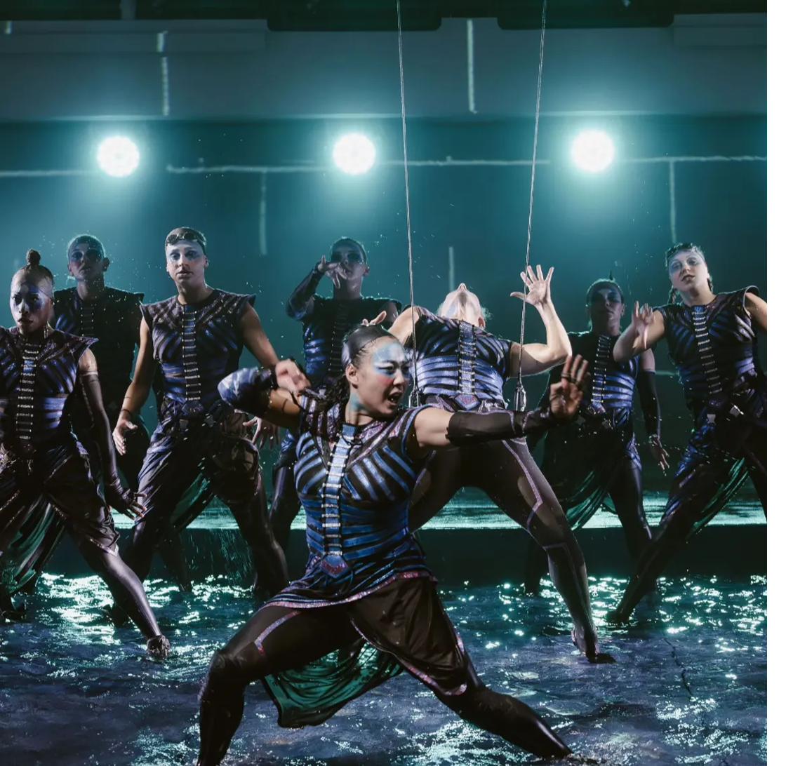Full cast performing on the illuminated stage