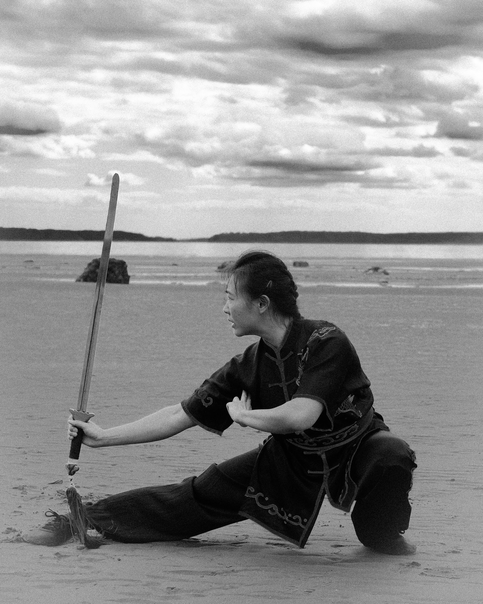 Black and white sword kneeling pose on a beach